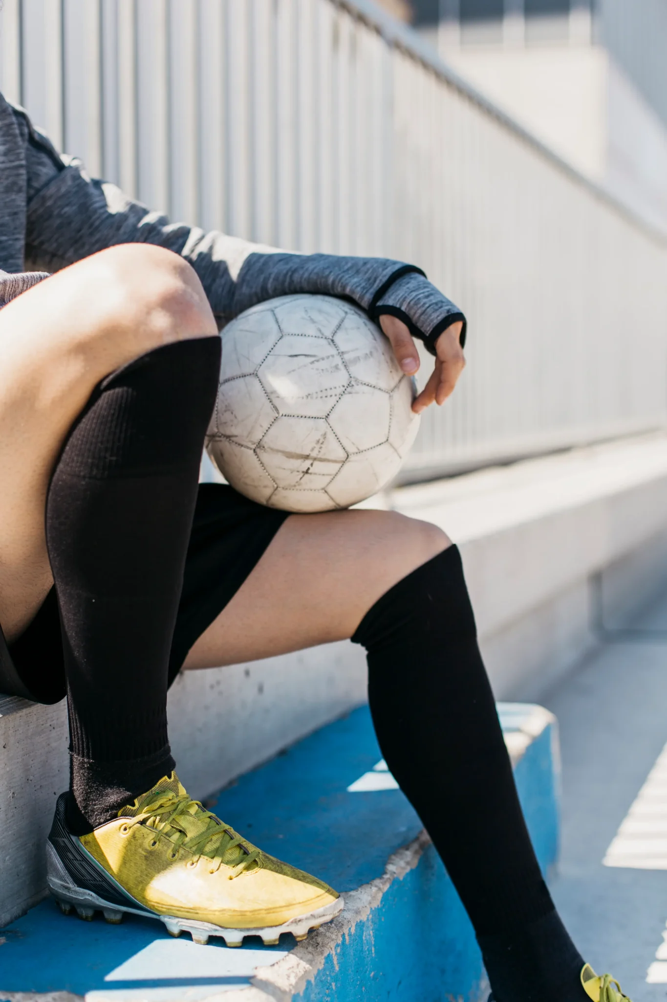 Atleta de futebol sentado na arquibancada segurando a bola